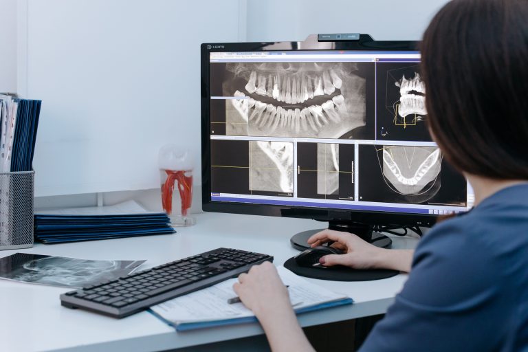Dentist examining dental X-rays on a computer screen in a clinic