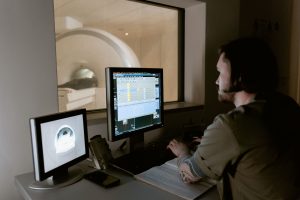 A radiologist examines MRI scan results on computer monitors in a medical facility