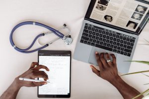 Healthcare professional reviews medical information on a laptop and tablet