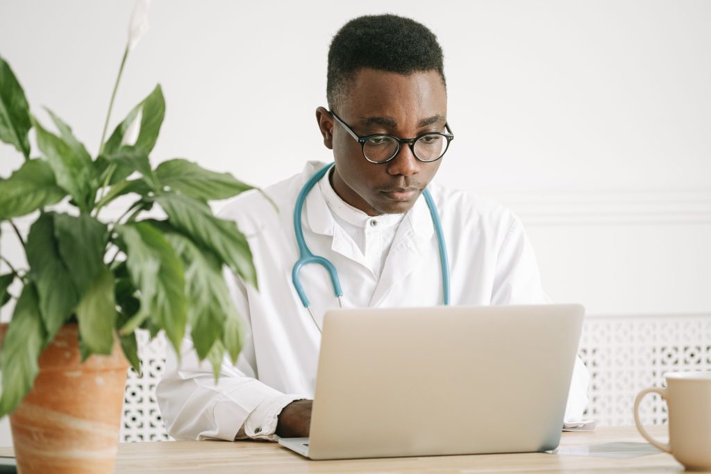 A doctor uses a laptop in a bright office