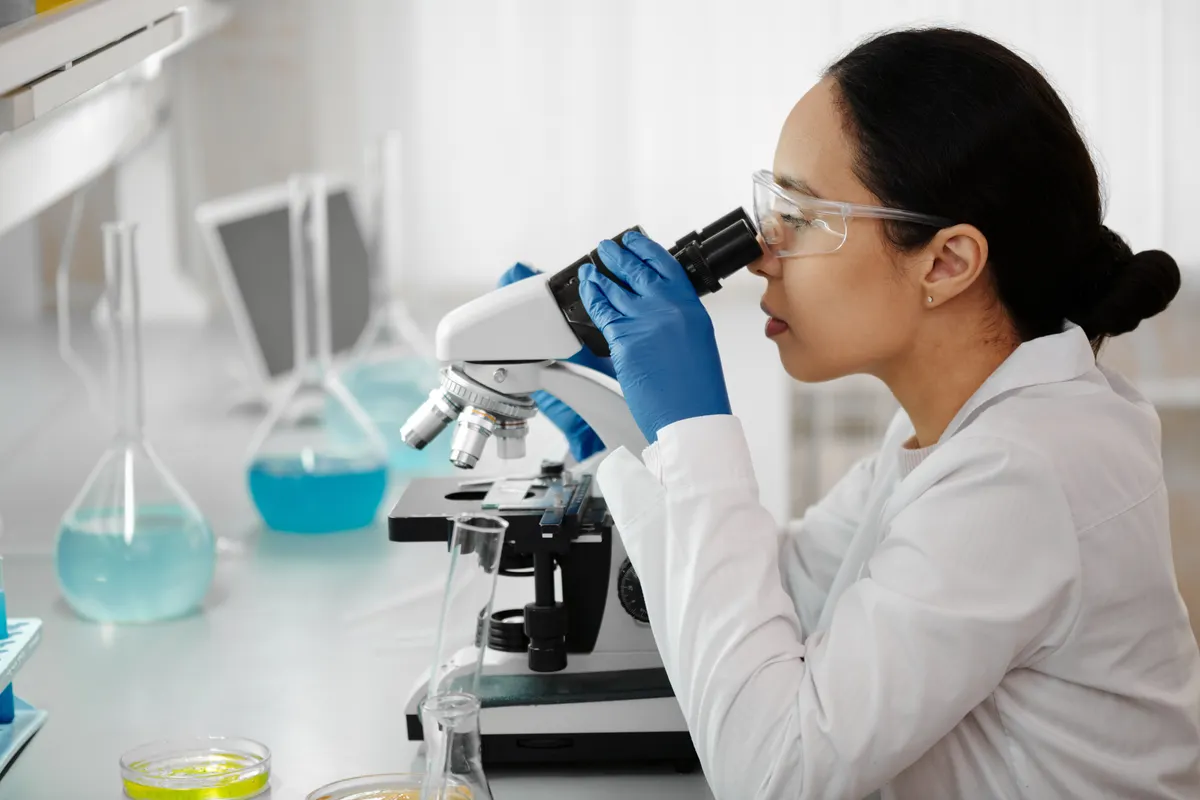 A researcher examines a sample through a microscope in a laboratory
