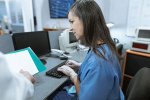 A nurse works at a computer in a clinical setting; illustrative stock photo