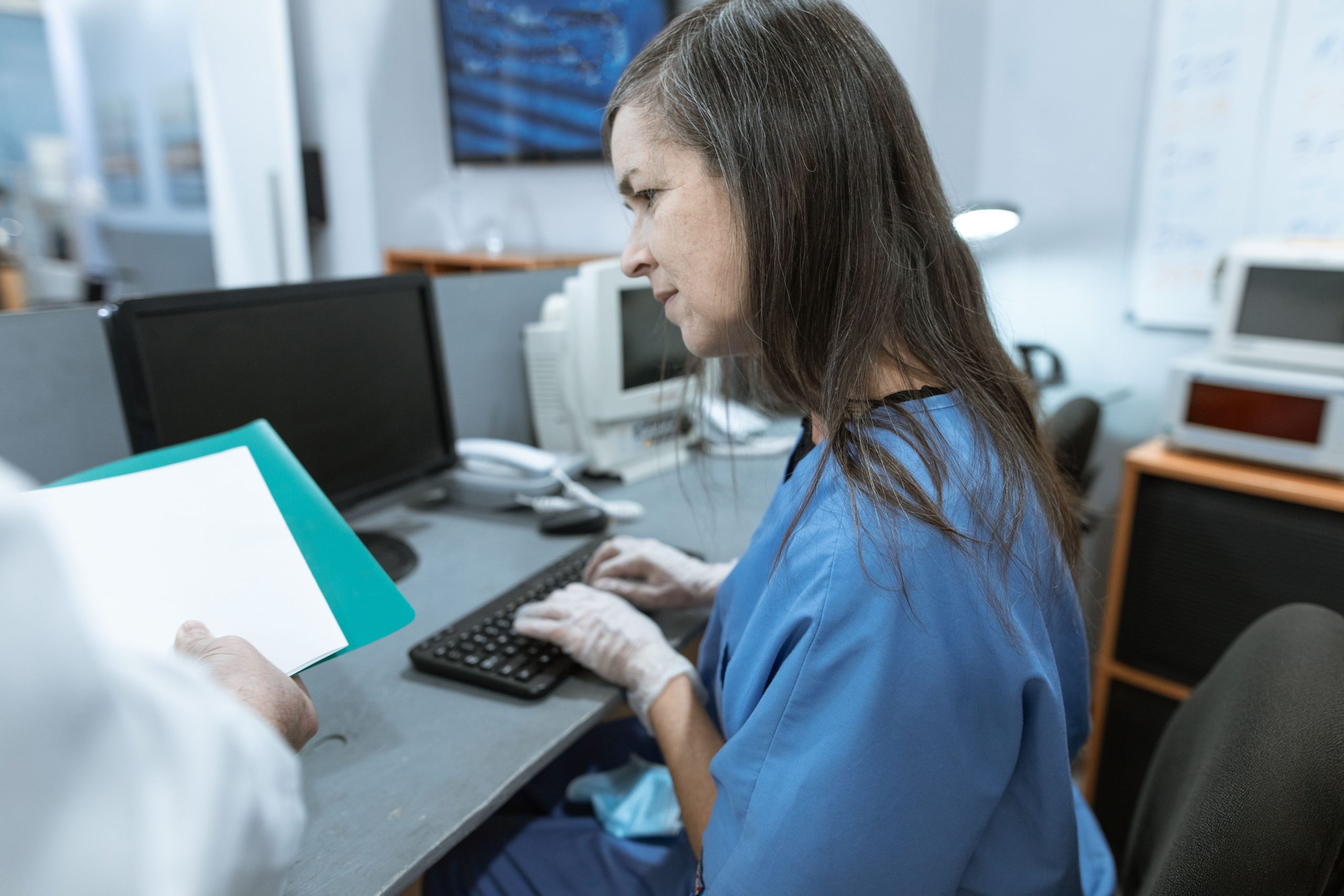 A nurse works at a computer in a clinical setting; illustrative stock photo