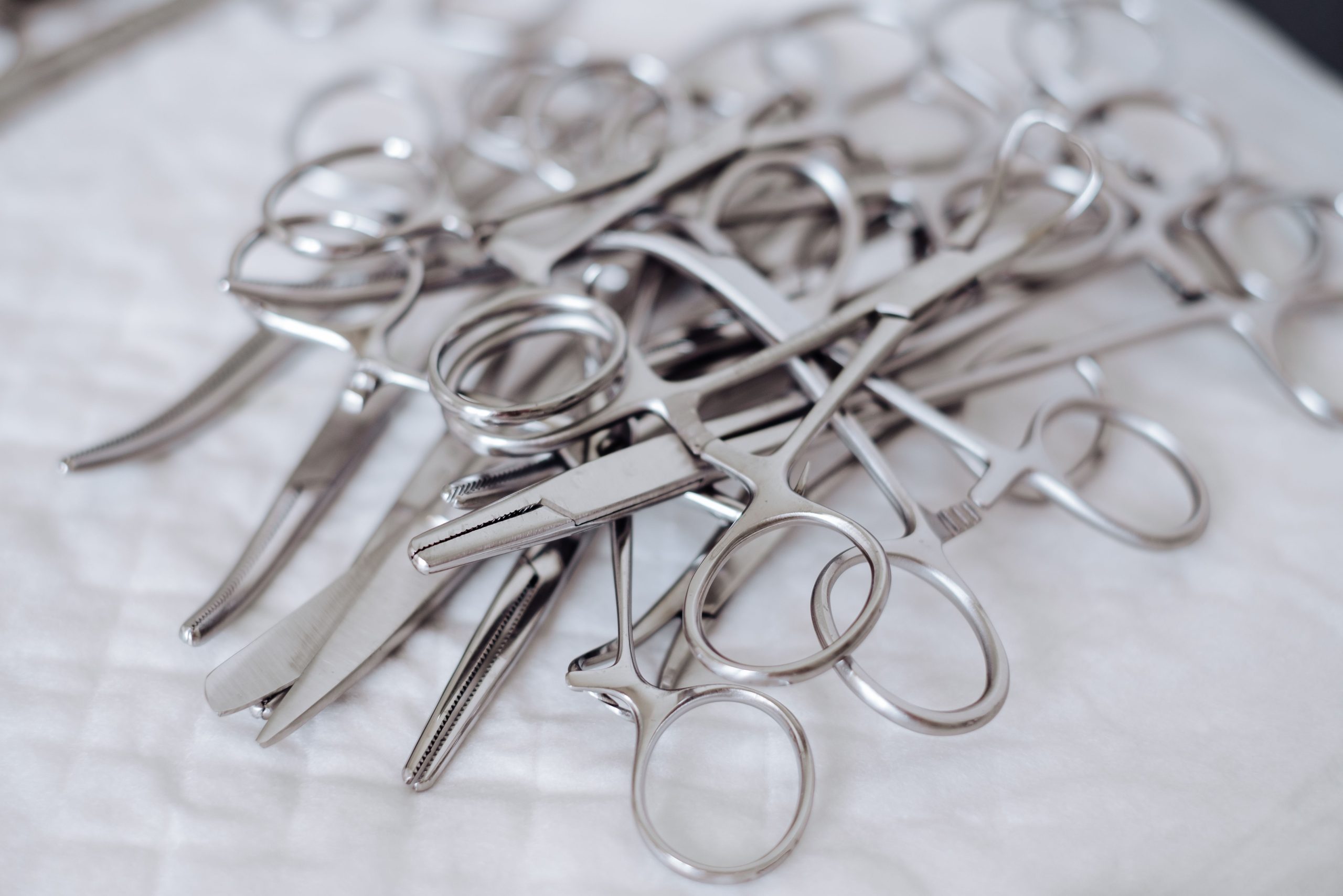Stainless steel surgical scissors and clamps lie on a white surface